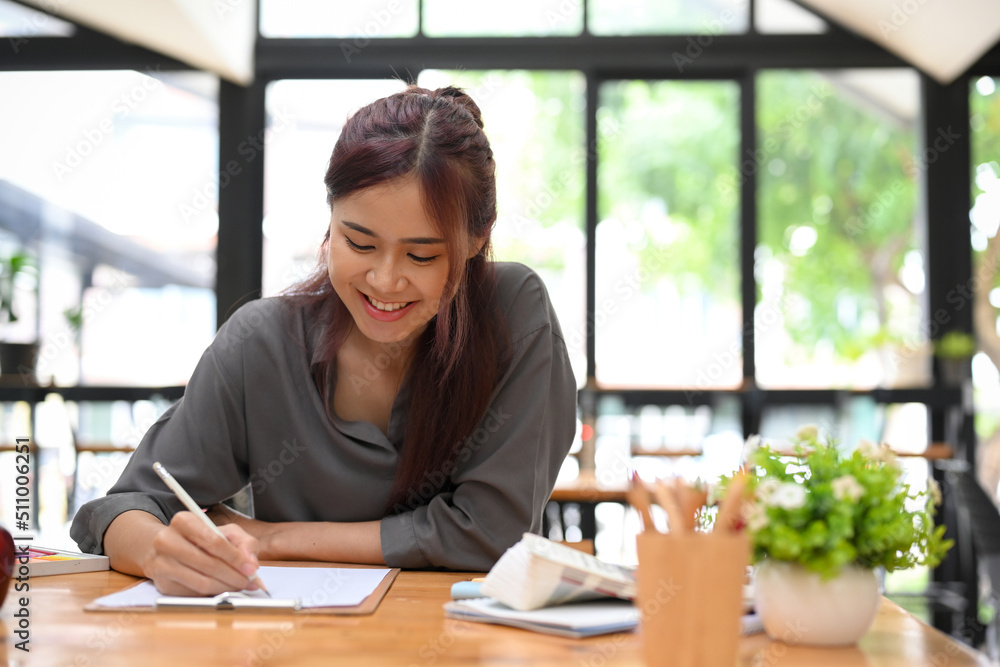 An asian female graphic designer sketching and designing her web design on blank paper An asian female graphic designer sketching and designing her web design on blank paper