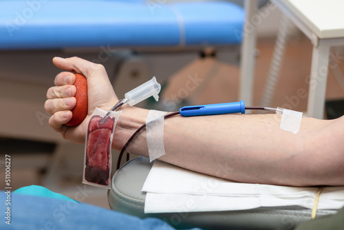 bone marrow donation. male hand holding red ball, man with blood transfusion system, blood bag. soft focus