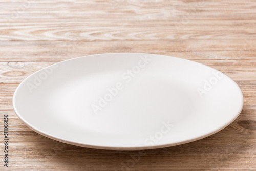 Perspective view of empty light plate on wooden background. Empty space for your design
