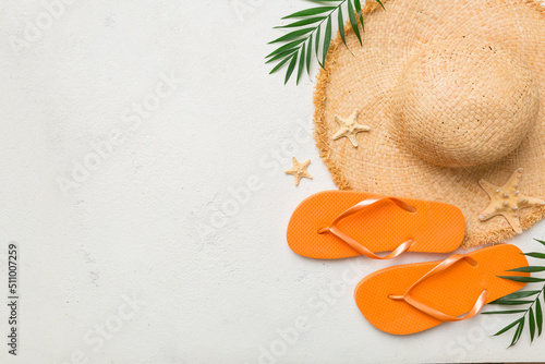 Summer travel concept. Flip flops, summer hat and starfish on white. Top view on colored background