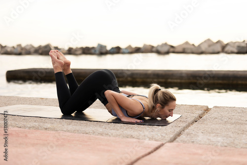 Beautiful young woman practising yoga outside. Fit woman doing yoga stretching exercises.
