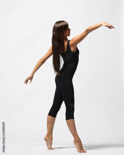 Young modern ballet woman dancer dancing on gray studio background