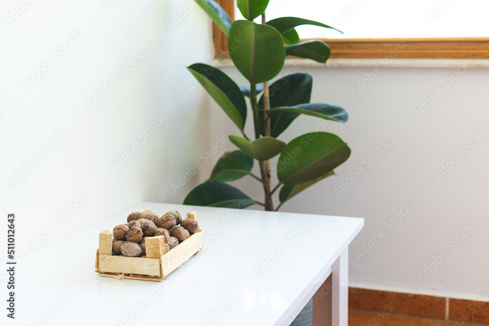 © zhukovvvlad - Wooden container with walnuts on a white table