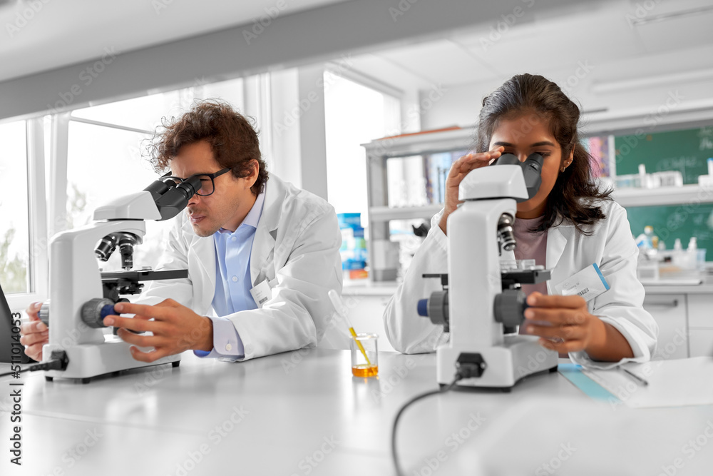 science research, work and people concept - international team of scientists with microscopes working in laboratory science research, work and people concept - international team of scientists with microscopes working in laboratory