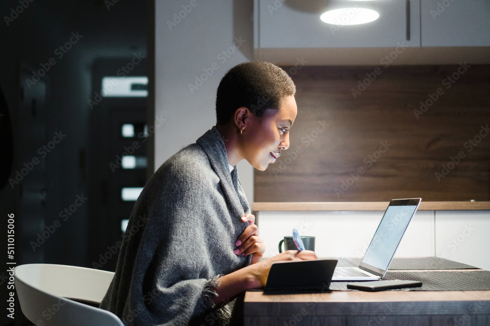 Young African American woman working late at night, from her home Young African American woman working late at night, from her home