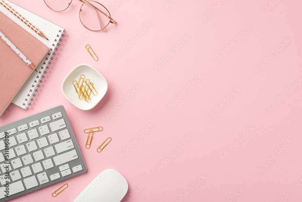 Business concept. Top view photo of workstation copybooks pencils keyboard computer mouse stylish glasses and clips on isolated pastel pink background with copyspace Business concept. Top view photo of workstation copybooks pencils keyboard computer mouse stylish glasses and clips on isolated pastel pink background with copyspace