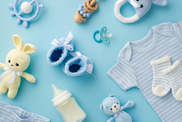 Baby accessories concept. Top view photo of infant clothes blue shirt knitted booties socks bunny and teddy-bear toys teether rattles milk bottle and pacifier on isolated pastel blue background