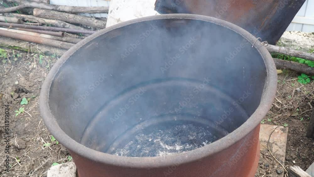 Light smoke rises from a rusty old barrel from burning garbage Light smoke rises from a rusty old barrel from burning garbage