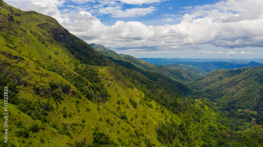 Aerial view of Mountains covered rainforest, trees and blue sky with clouds. Ella Rock, Sri Lanka.