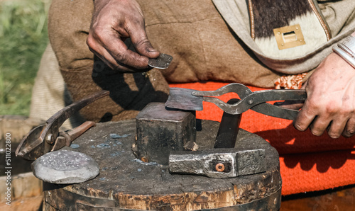 Blacksmith forges metal on an anvil with a hammer