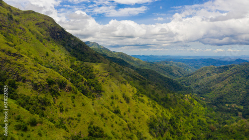 Aerial view of Mountains covered rainforest, trees and blue sky with clouds. Ella Rock, Sri Lanka.