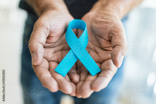 Senior man holding a blue cancer awareness ribbon