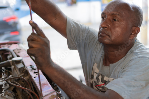 Male mechanic working on a vehicle at a car service station. Technician in car repair shop. © Hector Pertuz