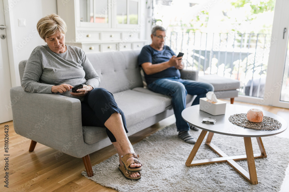 Senior couple using their mobile phones at home Senior couple using their mobile phones at home