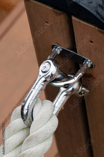 Shining stainless straght shackle with mooring rope tide up on the wood deck. Close up macro photography. photo