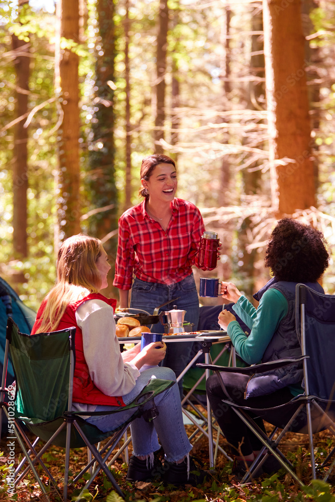 Group Of Female Friends On Camping Holiday In Forest Drinking Coffee Sitting By Tent Together Group Of Female Friends On Camping Holiday In Forest Drinking Coffee Sitting By Tent Together