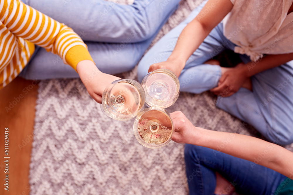 Close Up Of Female Friends Relaxing At Home Sitting In Lounge Celebrating With Glass Of Wine