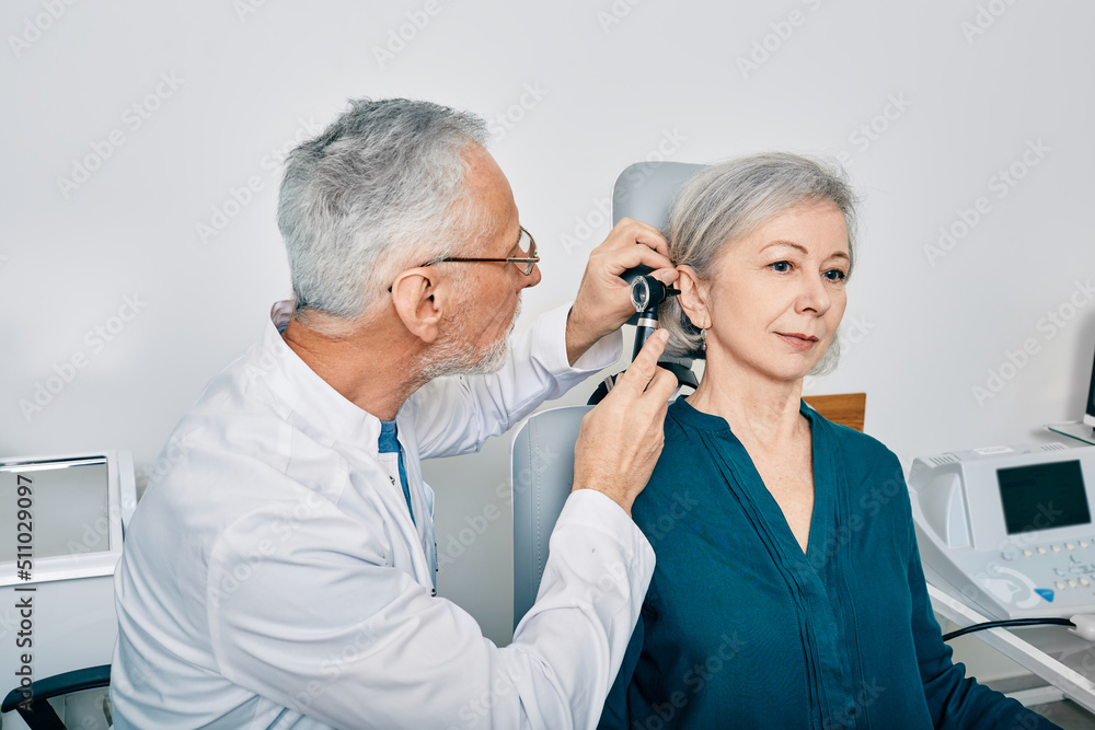 Foto de Otolaryngologist doctor checking senior woman's ear using