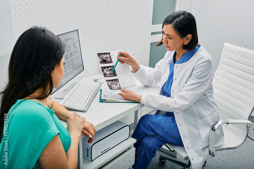 Doctor and woman patient is talking in gynecological office during visit at gynecology office. Consultation of gynecologist photo