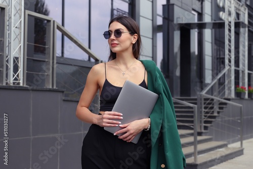 Portrait of a beautiful young woman with a laptop on the street