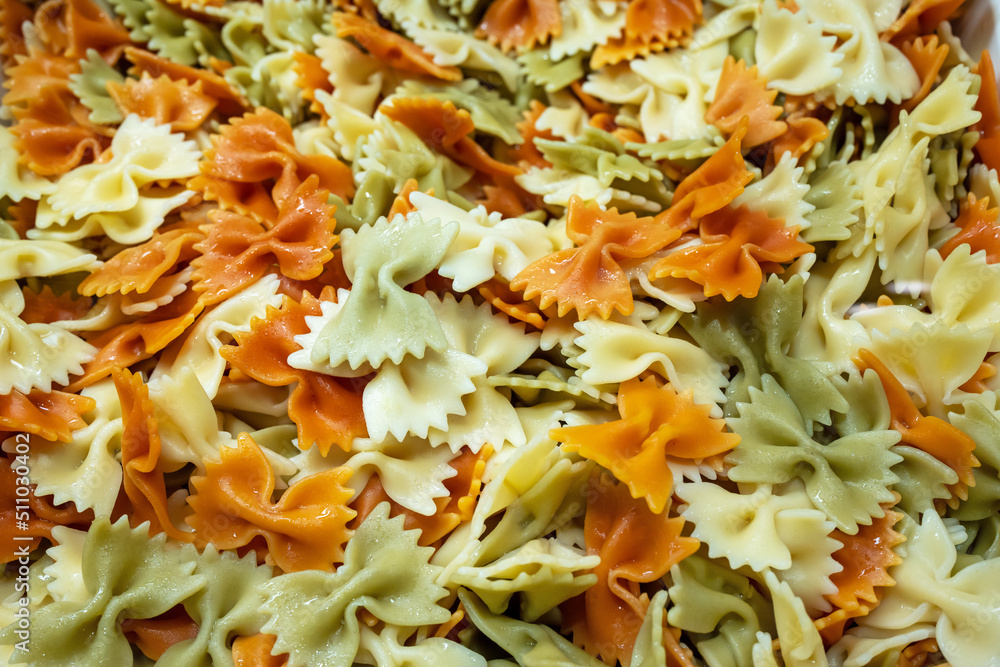 Pasta as a background. Cooked italian pasta Farfalle with oil. Colored pasta texture background. Top view. Tricolor pasta. Close up. Background carbohydrates food. Pasta as a background. Cooked italian pasta Farfalle with oil. Colored pasta texture background. Top view. Tricolor pasta. Close up. Background carbohydrates food.