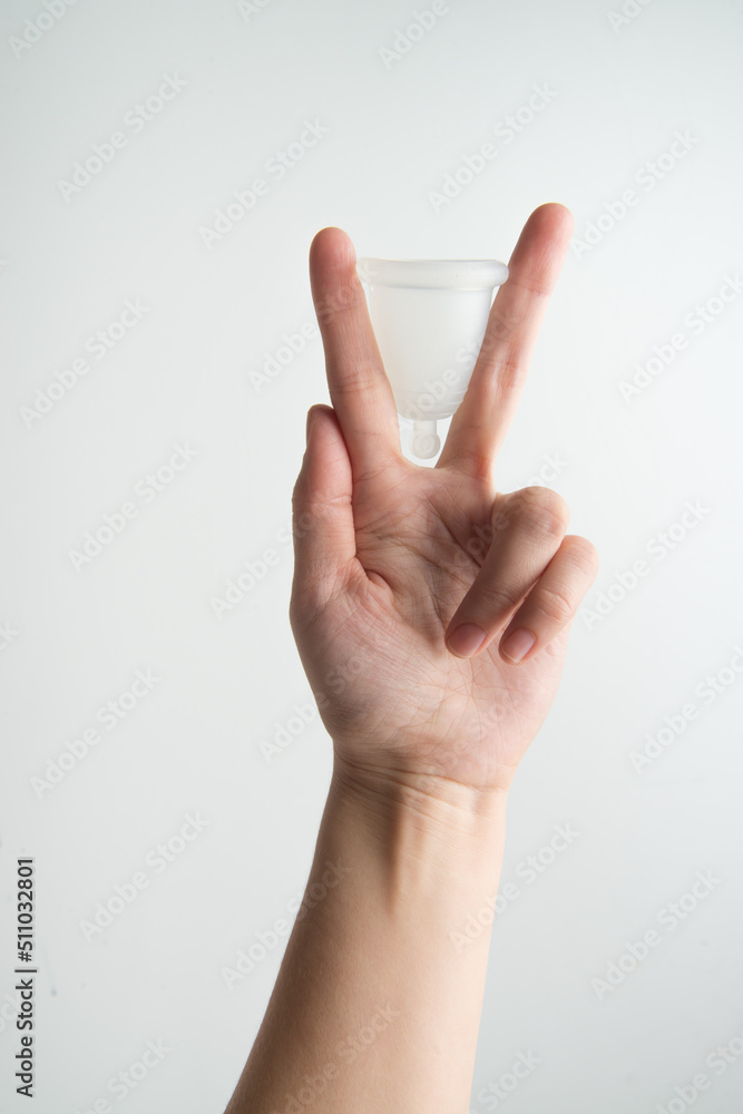 Naklejka premium the woman holds a menstrual cup in her hands 