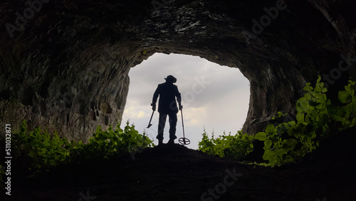 treasure hunter with metal detector searching inside the cave in the historical texture