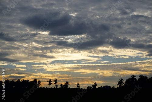 View of sunset ray with clouds in sky and silhouette of landscape foreground