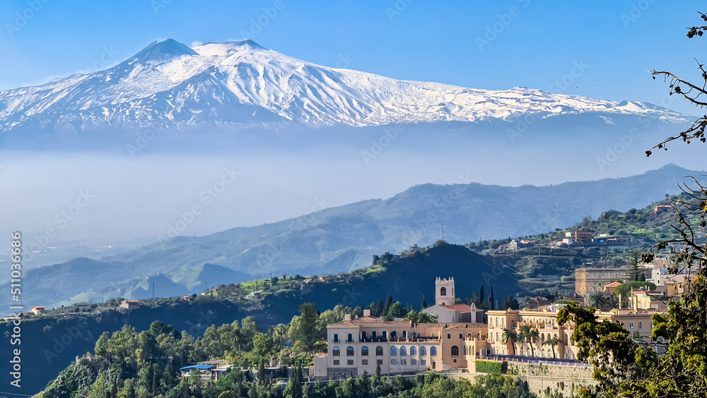 Luxury San Domenico Palace Hotel with panoramic view on snow capped Mount Etna volcano on sunny day from public garden Parco Duca di Cesaro to Giardini Naxos in Taormina, Sicily, Italy, Europe, EU