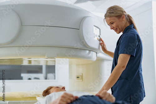 Radiologist controls MRI or CT Scan with patient undergoing procedure. High Tech medical equipment