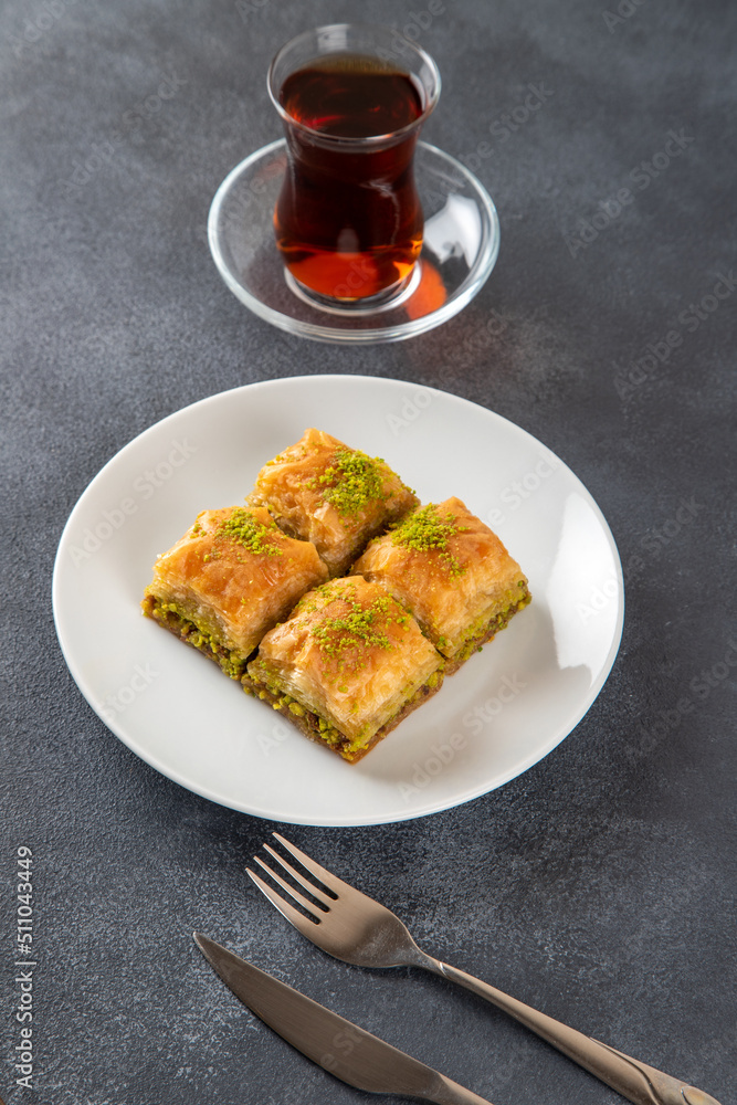 Pistachio baklava on a white plate with Turkish tea 