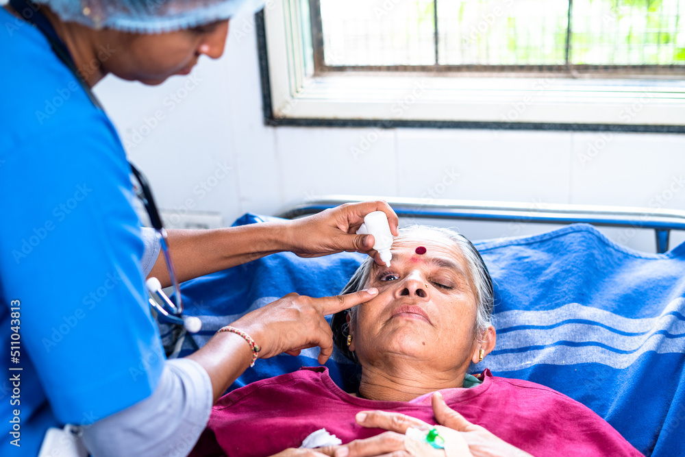 Nurse dripping eye drop to senior patient while sleeping on bed at hospital - concept of treatment, eye caring and professional occupation Nurse dripping eye drop to senior patient while sleeping on bed at hospital - concept of treatment, eye caring and professional occupation