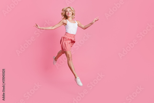 Full length body size view of attractive trendy cheerful slender girl jumping running isolated over pink pastel color background