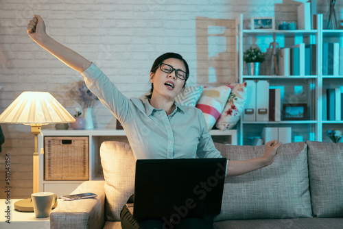 front view of asian business woman groaning while spreading her hands up in the air. korean lady at the halfway stage of her project is trying to kick up energy and stay awake by stretching photo