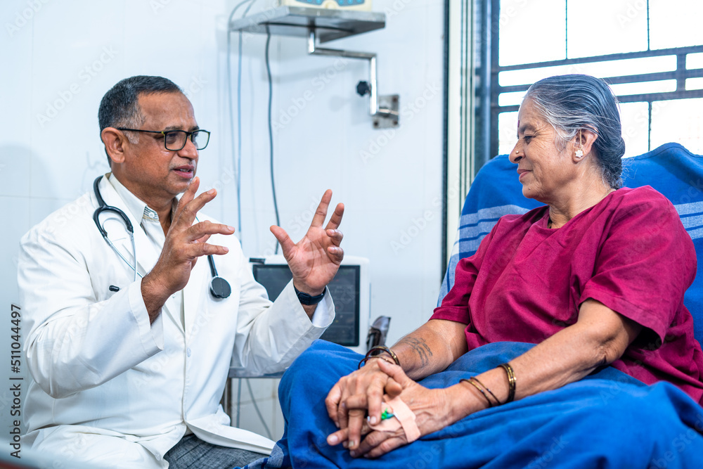 Obraz premium Doctor near patient bed advising to elderly woman at hospital - concept of diagnosis, confidence building and Mental illness.