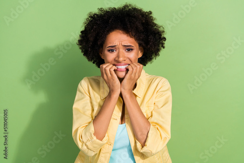 Photo of scared upset woman dressed yellow jeans jacket biting fingers isolated green color background