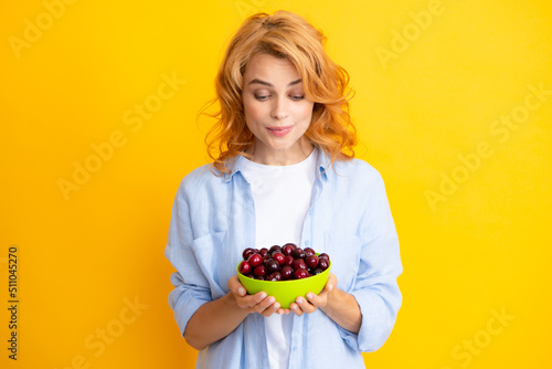 Womans enjoying a fresh sweet cherry. Female eating cherries on yellow background.