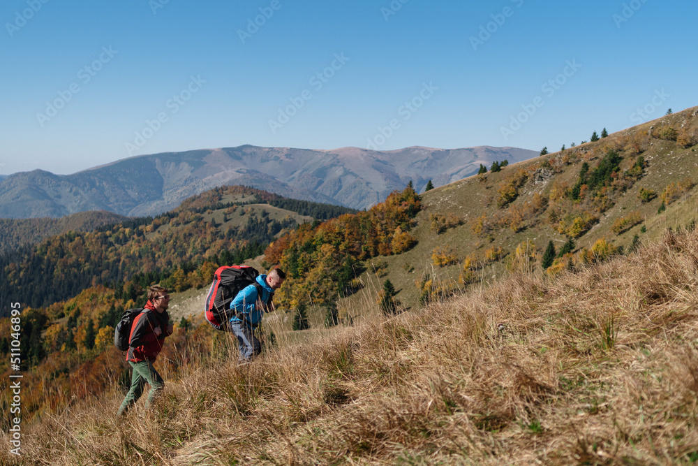 Obraz premium Paragliders, trekkers, mountaineers, walking up hill to a paragliding starting point, on a sunny morning in mountains.