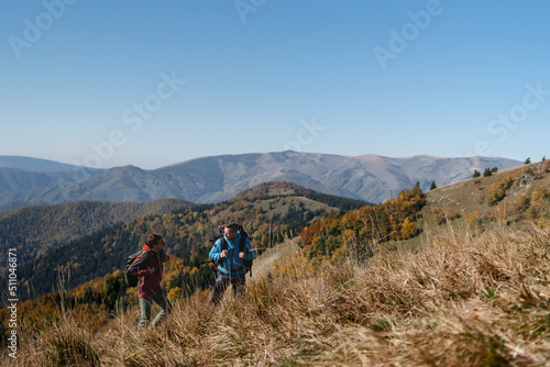 Paragliders, trekkers, mountaineers, walking up hill to a paragliding starting point, on a sunny morning in mountains.