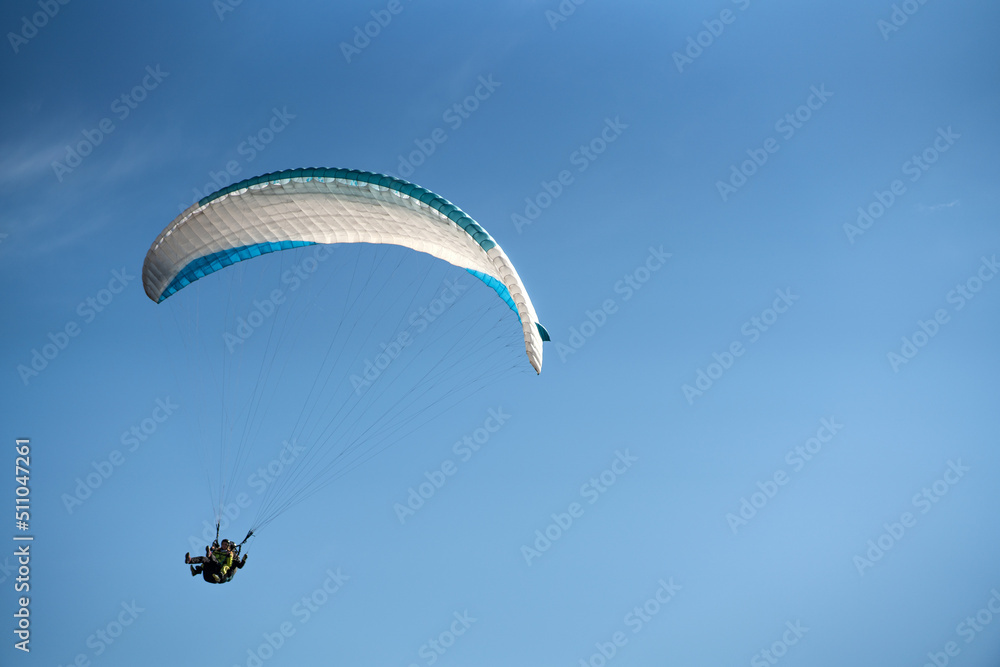 Paraglider in the blue sky. The sportsman flying on a paraglider. Paraglider in the blue sky. The sportsman flying on a paraglider.