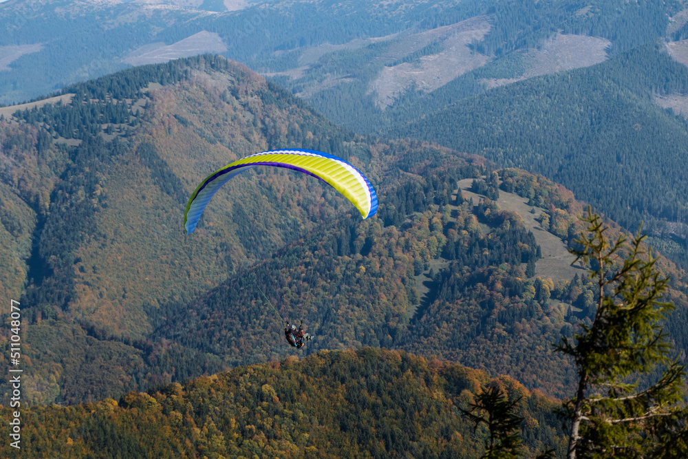 Paraglider flying in the blue sky with mountain in background. Paraglider flying in the blue sky with mountain in background.