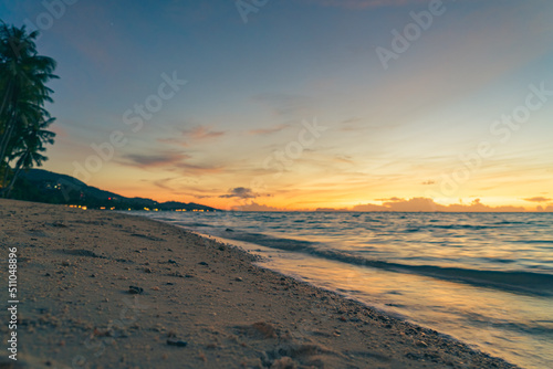 Sandy beach, surf and coastline at colorful sunset