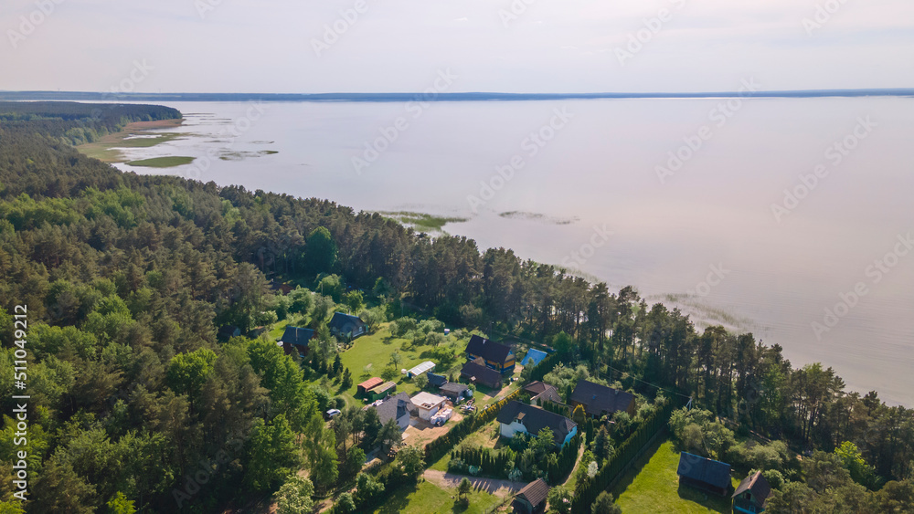 Obraz premium Aerial view of lake and small village. Village near the lake. Aerial view of the village and trees on the shore of lake.