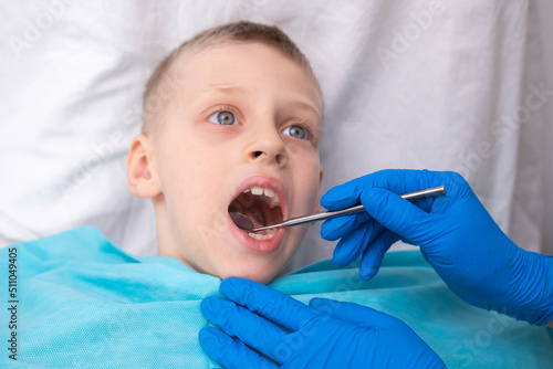 The dentist examines the child. Dentistry in children. The orthodontist examines the oral cavity of the kid. Sharp toothache. Caries on the teeth. Incorrect bite of teeth. photo