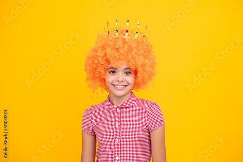 Little queen in wig wearing golden crown. Teenage girl princess holding crown tiara. Prom party, childhood concept.