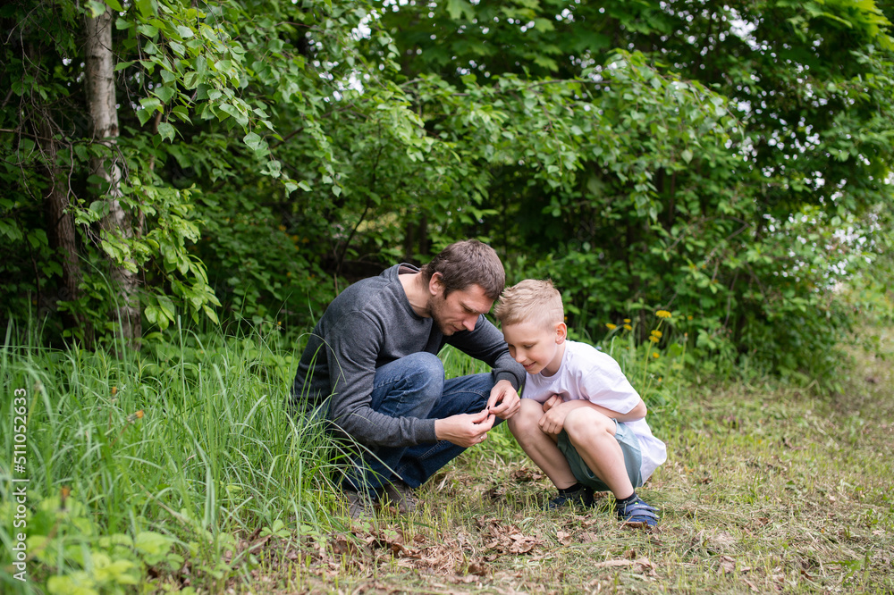 The boy is sitting next to his dad, looking at the ground The boy is sitting next to his dad, looking at the ground