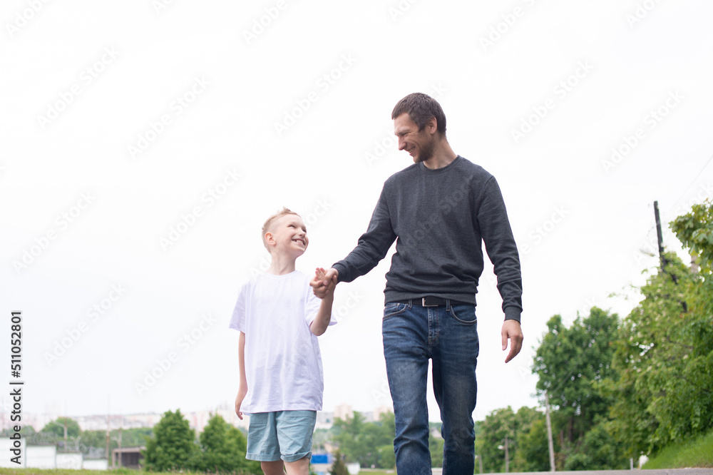 A father walks with his son on the road. The child is indulging A father walks with his son on the road. The child is indulging