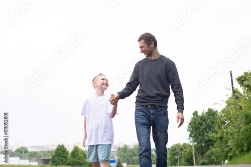 A father walks with his son on the road. The child is indulging