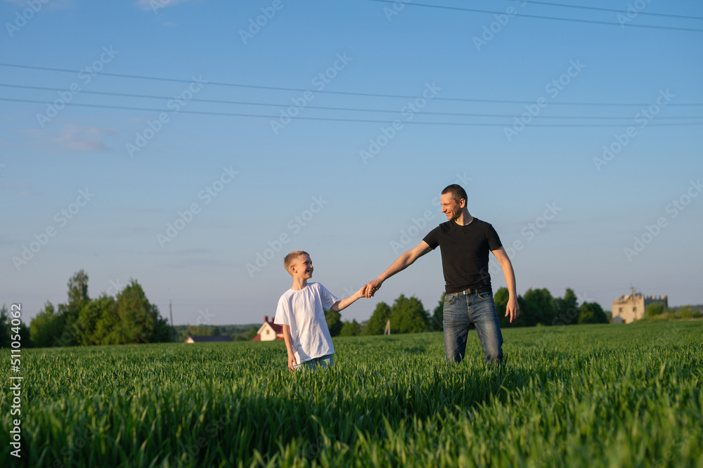 A cute child holds his father's hand and they go into the field