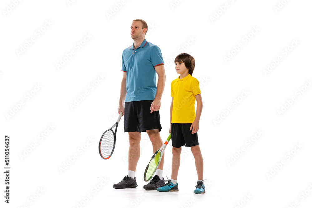 Professional tennis player, instructor and school age boy wearing sports uniform standing together isolated over white background. Concept of sport, achievements, hobby, skills Professional tennis player, instructor and school age boy wearing sports uniform standing together isolated over white background. Concept of sport, achievements, hobby, skills